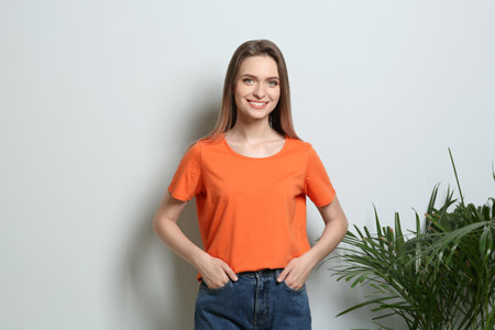 Young woman wearing blank t-shirt on light background. Mockup for designの写真素材