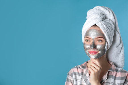Young woman with cleansing mask on her face against color background, space for text. skincareの写真素材