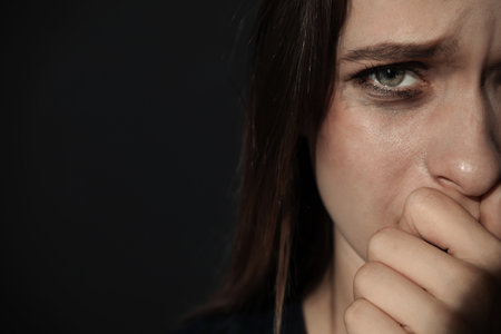 Crying young woman on dark background, space for text. stop violenceの写真素材
