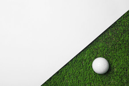 Golf ball and white paper on green artificial grass, top view with space for textの写真素材