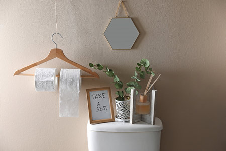 Decor elements, necessities and toilet bowl near beige wall. Bathroom interiorの写真素材
