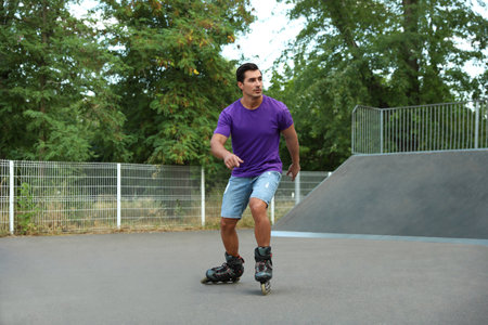 Handsome young man roller skating in park