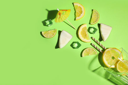 Flat lay composition with glass, ice, sliced fruits and coconut on green background. Summer cocktail recipeの写真素材