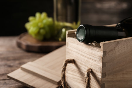 Open wooden crate with bottle of wine on blurred background, space for textの写真素材