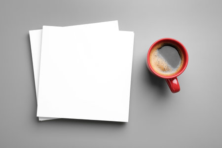 Blank paper sheets for brochure and cup of coffee on grey background, flat lay. Mock up