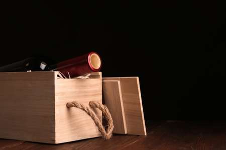 Open wooden crate with bottle of wine on table, space for textの写真素材