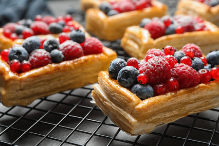 Cooling rack and fresh delicious puff pastry with sweet berries on grey table, closeupの写真素材
