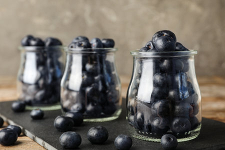 Jars of fresh acai berries on black board, closeup. Space for textの写真素材