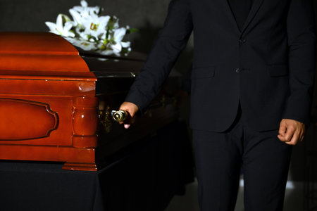 Young man carrying wooden casket in funeral home, closeupの写真素材