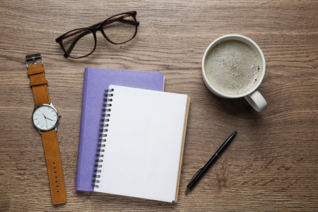 Flat lay composition with office stationery and cup of coffee on wooden table. Space for design