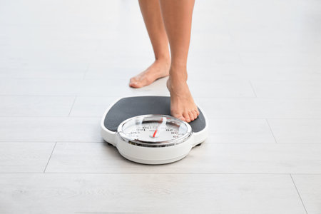 Woman standing on scales indoors. Overweight problemの写真素材
