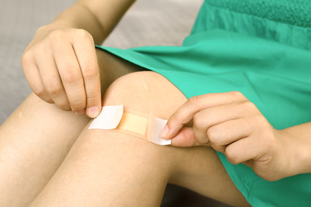 Woman applying plaster on knee, closeup viewの写真素材