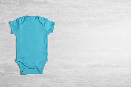 Baby bodysuit on wooden background, top view. Space for textの写真素材