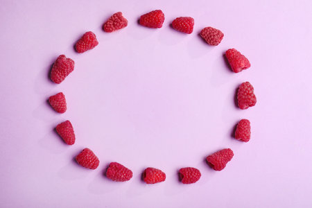 Frame made of tasty raspberries on lilac background, top view with space for textの写真素材