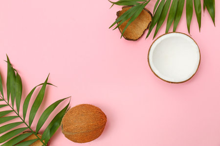 Fresh coconuts and palm leaves on pink background, flat lay. Space for textの写真素材