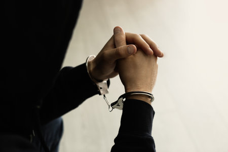Man detained in handcuffs indoors, closeup view. Criminal lawの写真素材