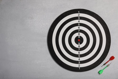 Dart board with color arrows on light stone background, top view. Space for textの写真素材