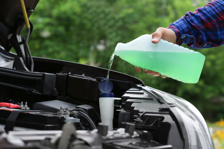 Man pouring liquid from plastic canister into car washer fluid reservoir, closeupの写真素材