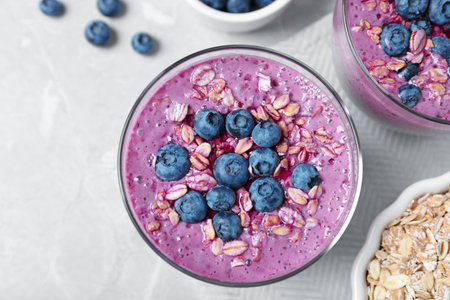 Glass of tasty blueberry smoothie with muesli on grey marble table, flat layの写真素材
