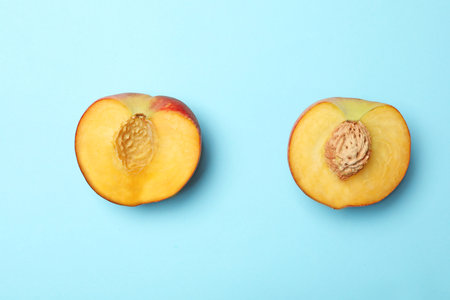 Halves of sweet juicy peach on light blue background, top viewの写真素材