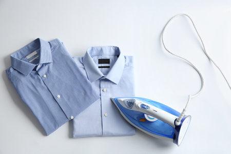 Iron with clean shirts on light background, top viewの写真素材