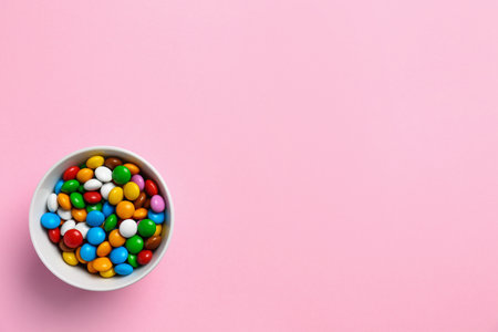 Delicious bright glazed candies on pink background, top view. Space for text