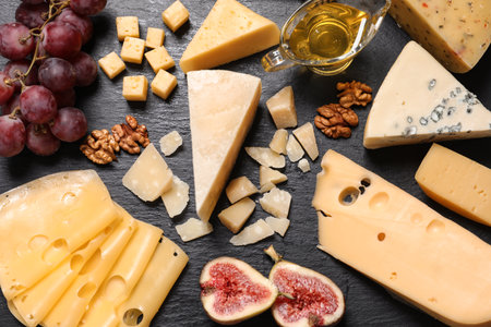 Flat lay composition with different types of delicious cheese on slate board