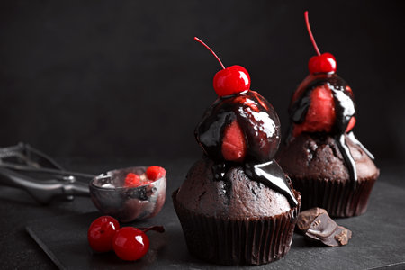 Delicious chocolate muffins with sweet syrup, ice cream and cherries on table. Space for textの写真素材