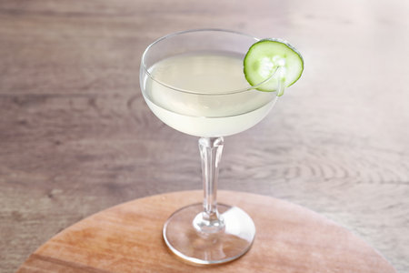 Glass of tasty cucumber martini on wooden tableの写真素材
