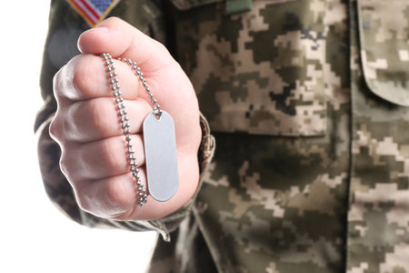 Man in camouflage uniform holding military ID tag on white background, closeupの写真素材