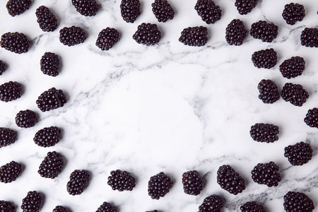 Frame made of tasty blackberries on marble table, top view with space for textの写真素材