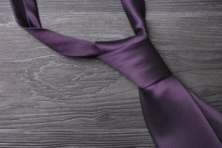 Stylish purple silk necktie on dark gray wooden table, top viewの写真素材