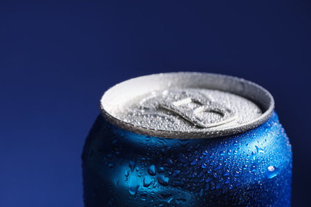 Aluminum can of beverage covered with water drops on blue background, closeup. Space for textの写真素材