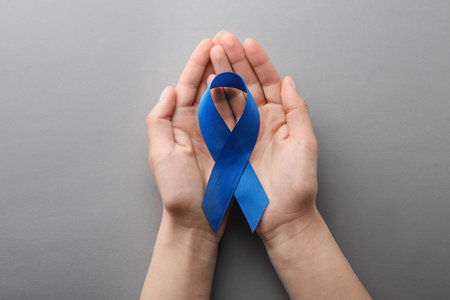 Woman holding blue awareness ribbon on gray background, top viewの写真素材