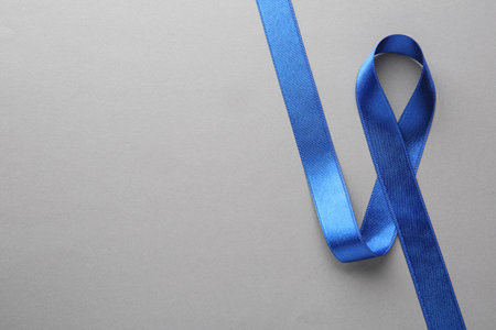 Blue awareness ribbon on gray background, top view with space for text. Symbol of social and medical issuesの写真素材