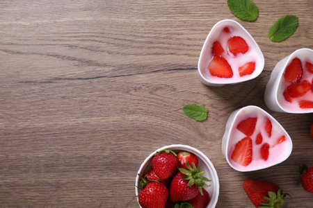 Cups of homemade yogurt and strawberries on wooden table, flat lay with space for text. Recipe for multi-cookerの写真素材