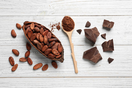 Flat lay composition with cocoa beans, spoon of powder and chocolate on white wooden tableの写真素材
