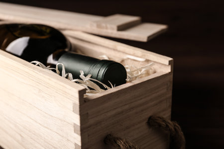 Open wooden crate with bottle of wine on dark background, closeupの写真素材