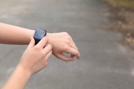 Young woman checking pulse with smartwatch on street, closeup. Space for textの写真素材