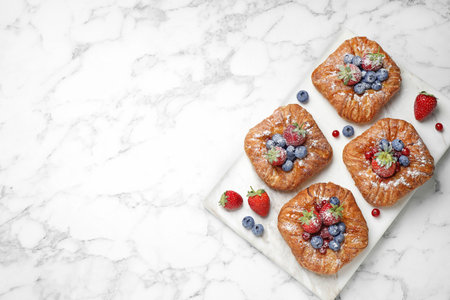 Fresh delicious puff pastry with sweet berries on white marble table, top view. Space for textの写真素材