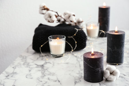 Burning candles and cotton flower with fairy lights on marble tableの写真素材
