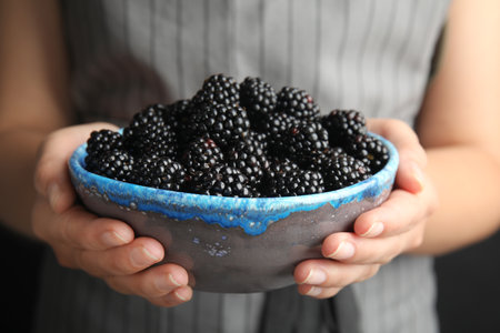 Young woman holding bowl of ripe blackberries, closeupの写真素材