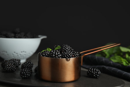Metal saucepan with tasty blackberries on slate plateの写真素材
