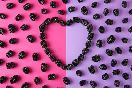 Heart shaped frame made of tasty blackberries on color background, top view with space for text