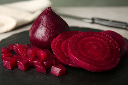 Slate plate with cut boiled beets on table, closeup