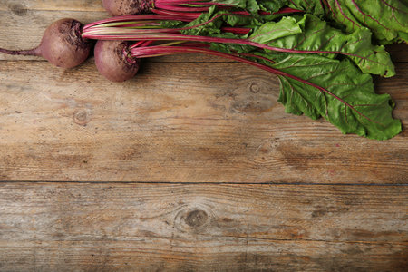 Fresh beets with leaves on wooden table, flat lay. Space for textの写真素材