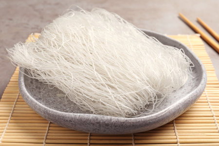 Plate with tasty raw rice noodles on bamboo mat