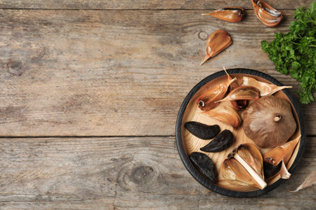 Flat lay composition with black garlic and space for text on wooden tableの写真素材