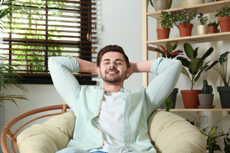 Young man resting in room with different home plantsの写真素材