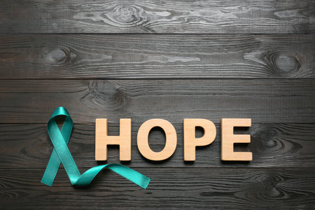 Word Hope made of letters and teal awareness ribbon on wooden background, top view. Symbol of social and medical issuesの写真素材